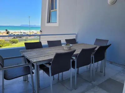 a wooden table and chairs with a view of the beach at 109 da Gama on Beach in Strand