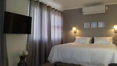 a bedroom with a bed and a flat screen tv at 29 Carissa Street in Somerset West