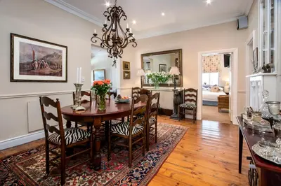 a dining room and living room with a table and chairs at La Fontaine Guest House Hermanus in Hermanus