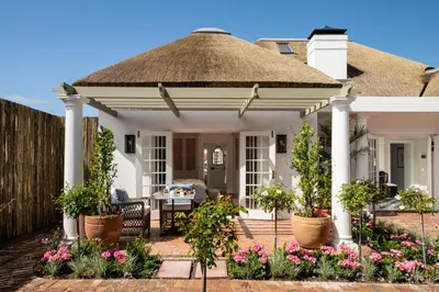 a white house with a thatched roof at La Fontaine Guest House Hermanus in Hermanus