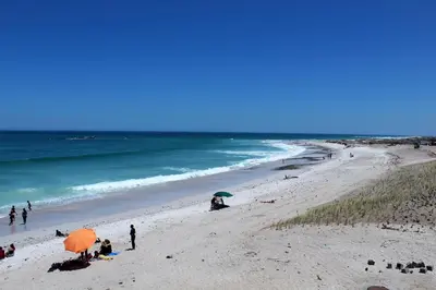 a group of people on a beach with umbrellas at 605 Nautica in Bloubergstrand