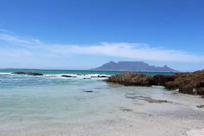 a beach with rocks and a mountain in the background at 605 Nautica in Bloubergstrand