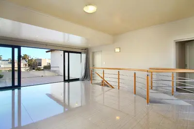 a living room with a table and a balcony at Sunset at Granula in Cape Town