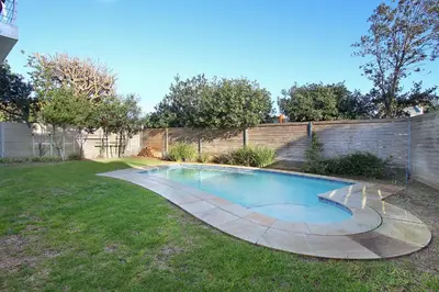 a swimming pool in a yard with a fence at Sunset at Granula in Cape Town