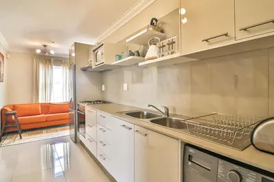 a kitchen with a sink and an orange couch at Kwantu Guesthouse 2 in Cape Town