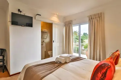 a bedroom with a bed with a television on the wall at Kwantu Guesthouse 2 in Cape Town