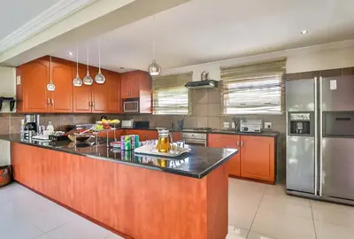 a large kitchen with wooden cabinets and stainless steel appliances at Kwantu Guesthouse 2 in Cape Town