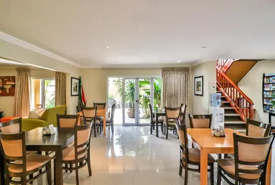 a restaurant with tables and chairs and a staircase at Kwantu Guesthouse 2 in Cape Town