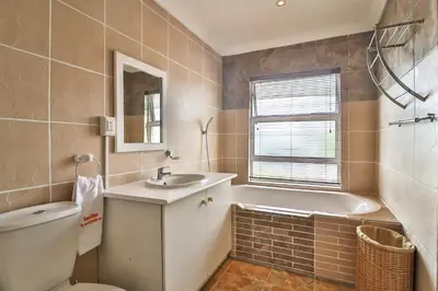 a bathroom with a tub and a sink and a toilet at Kwantu Guesthouse 2 in Cape Town