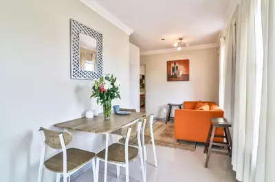 a dining room and living room with a table and chairs at Kwantu Guesthouse 2 in Cape Town