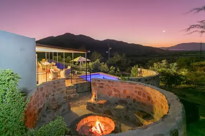 a patio with a brick fire pit in front of a house at Olive Hill Guest House in Robertson