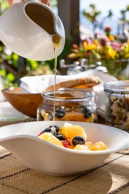 a bowl of fruit being drizzled with syrup at Angala in Simondium