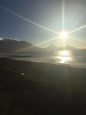 a sun setting over the ocean with mountains in the background at 325 Leisure Bay Cape Town in Cape Town