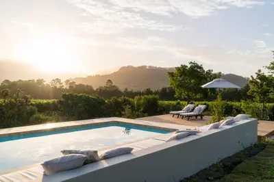 a swimming pool with chairs and a table at Cape Vue Country House in Franschhoek