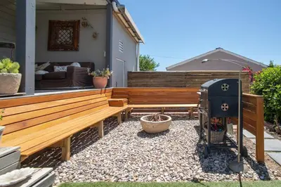 a backyard with a wooden bench and a grill at 29 Earlibelle in Stellenbosch