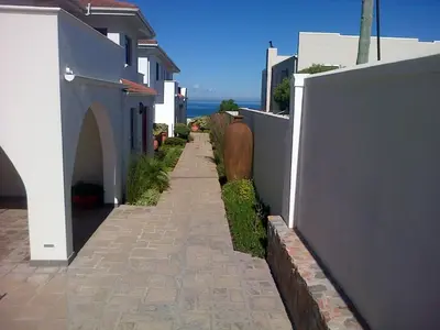 a walkway between buildings with the ocean in the background at Pelagus Guest House in Hermanus