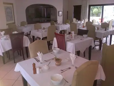 a dining room with tables and chairs with white tablecloths at Pelagus Guest House in Hermanus