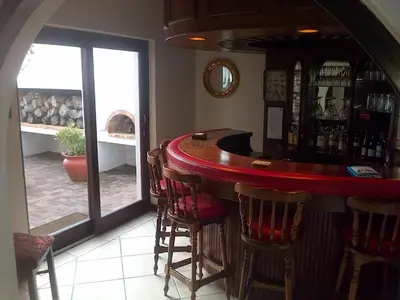 a bar with a red counter and some chairs at Pelagus Guest House in Hermanus