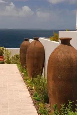 four large vases are lined up against a wall at Pelagus Guest House in Hermanus