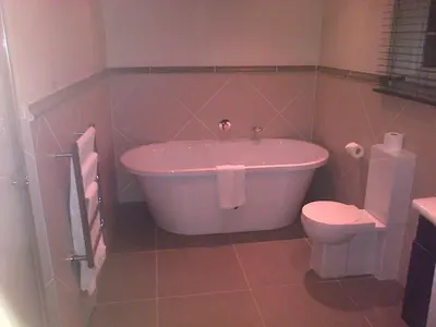 a bathroom with a tub and a toilet at Nautilus Guest House in Hermanus