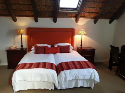 a bedroom with a large bed with red pillows at Nautilus Guest House in Hermanus