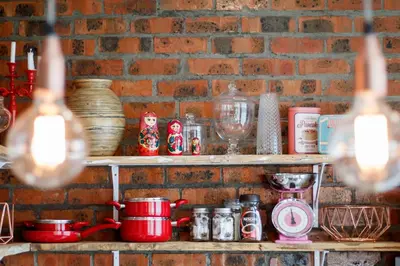 a brick wall with shelves with pots and pans at Rustic Retreat Apartment in Durbanville in Durbanville