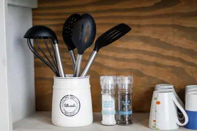 a white container with utensils sitting on a shelf at Rustic Retreat Apartment in Durbanville in Durbanville