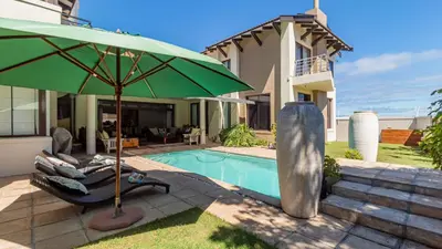 a green umbrella sitting next to a swimming pool at Atlantic Waves Guest House in Cape Town
