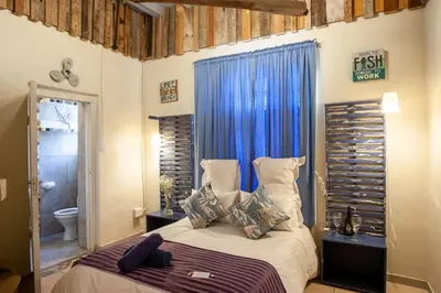 a bedroom with a bed with a blue curtain at Bedrock Guest Studios in Strand