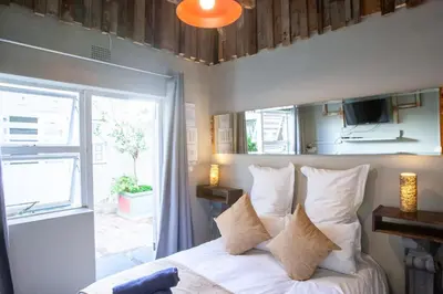 a bedroom with a bed with white pillows and a window at Bedrock Guest Studios in Strand