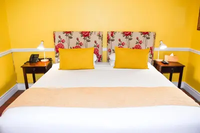 a bedroom with a bed with yellow walls and yellow pillows at Knorhoek Country Guesthouse in Stellenbosch