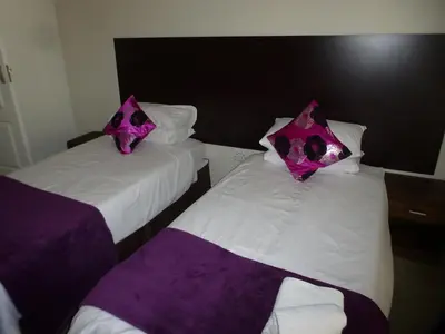 two beds in a hotel room with purple pillows at Cape Town Milnerton Lagoon Villa in Cape Town