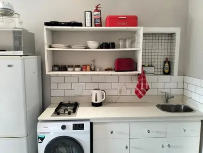 a kitchen with a sink and a washing machine at Feet Up Cottage in Somerset West