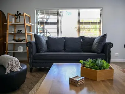 a living room with a black couch and a table at Atlantic Oasis Guest House in Table View