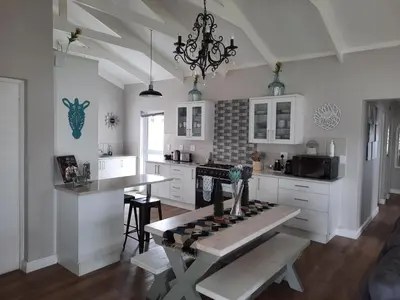 a kitchen with white cabinets and a table in it at Heavenly Breeze in Hermanus