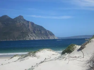 a sandy beach with the ocean and a mountain at Nagua bay in Gordonʼs Bay