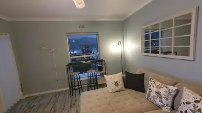 a living room with a couch and a window at Nagua bay in Gordonʼs Bay