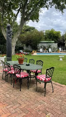 a patio table with four chairs and a table with flowers at Brooklands House in Cape Town