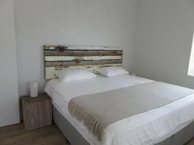 a bedroom with a large bed with a wooden headboard at Irene Avenue Apartment with sea views in Somerset West