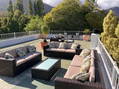 a patio with couches and tables on a roof at Hotel du Vin Franschhoek in Franschhoek