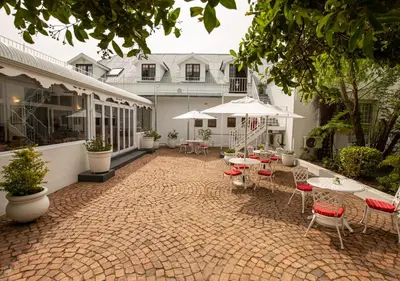 an outdoor patio with tables and chairs and umbrellas at Hotel du Vin Franschhoek in Franschhoek