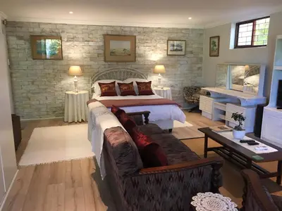a bedroom with a bed and a couch in a room at Geranium Studio in Somerset West