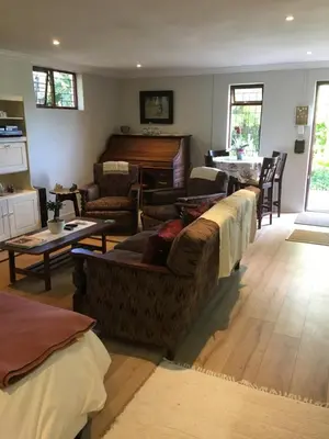 a living room with a group of couches and a piano at Geranium Studio in Somerset West