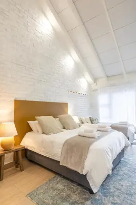a bedroom with a large bed and a brick wall at Rouana Guest Farm in Stellenbosch