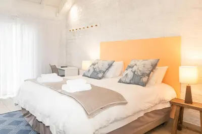 a bedroom with a large white bed with two pillows at Rouana Guest Farm in Stellenbosch