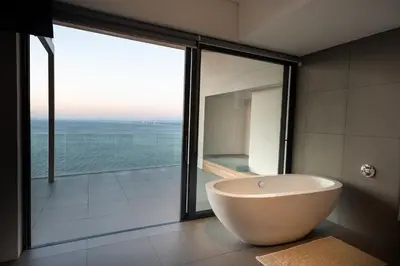a bath tub in a bathroom with a large window at '22 Protea' - Luxury, Style and Elegance - Sleeps 12 in 6 En-suite Bedrooms in Gordonʼs Bay