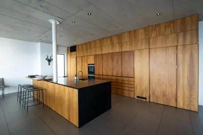 a kitchen with a black island and wooden cabinets at '22 Protea' - Luxury, Style and Elegance - Sleeps 12 in 6 En-suite Bedrooms in Gordonʼs Bay