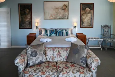 a bedroom with a bed and a couch in front of it at Die Badhuis, for Fabulous living! Sleeps 4, Private pool in Gordonʼs Bay