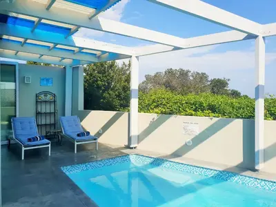 a swimming pool with two chairs and a pergola at Die Badhuis, for Fabulous living! Sleeps 4, Private pool in Gordonʼs Bay