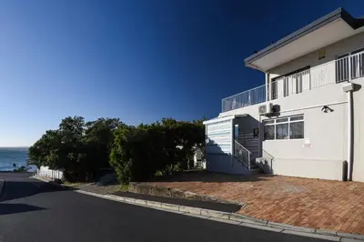 a white house with the ocean in the background at Die Badhuis, for Fabulous living! Sleeps 4, Private pool in Gordonʼs Bay